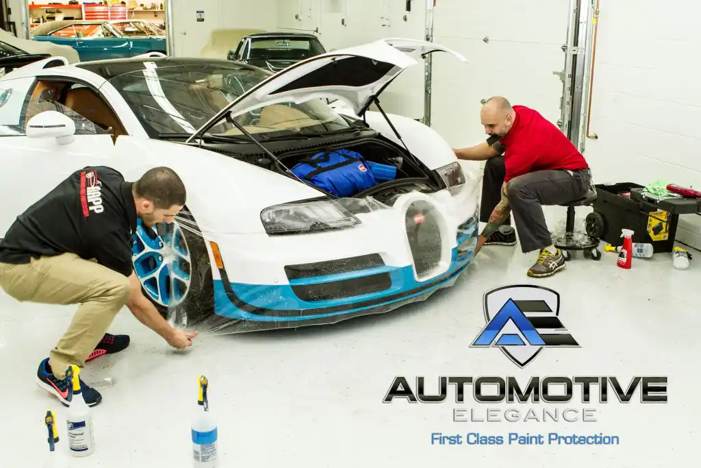 Technicians installing paint protection film on the front bumper of a Bugatti Veyron