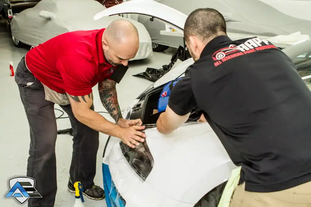Technicians installing paint protection film around the headlight of a Bugatti Veyron