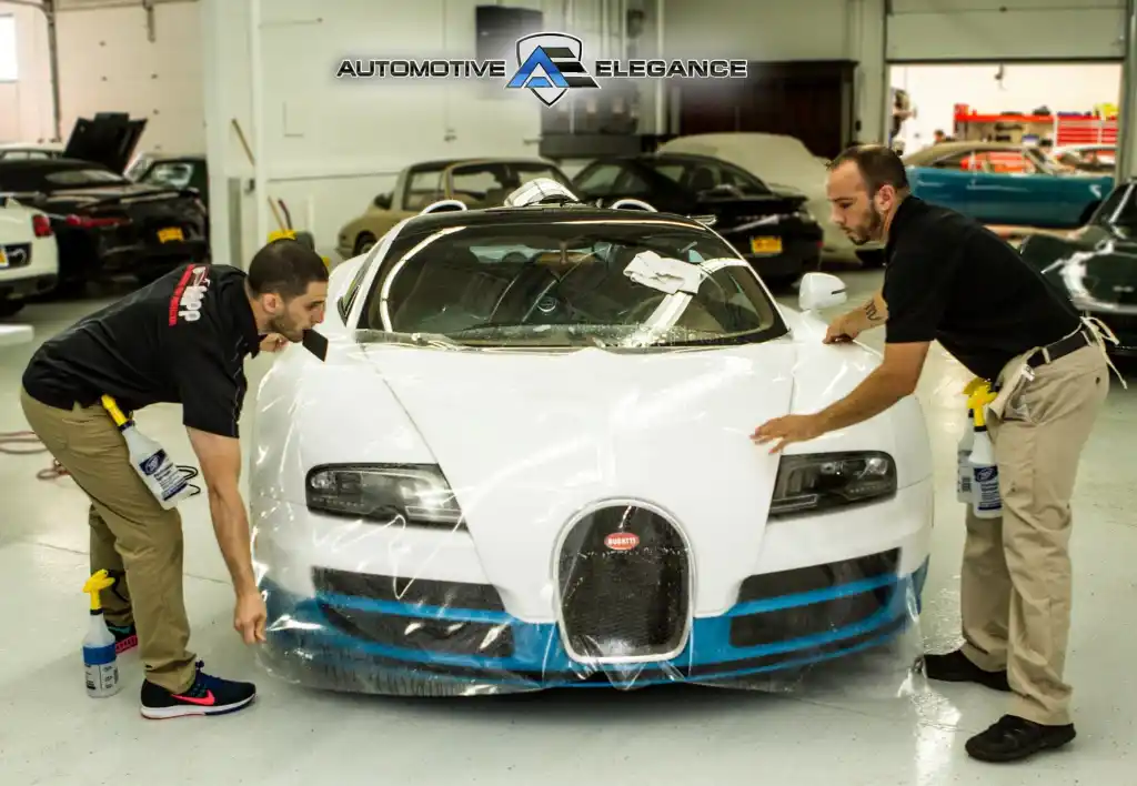 Technicians applying paint protection film to the front of a Bugatti Veyron