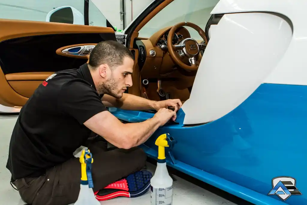 Technician applying paint protection film to the lower side panel of a Bugatti Veyron