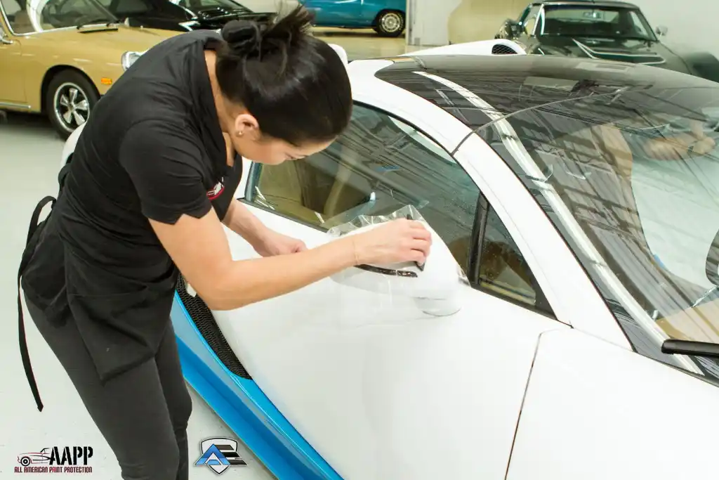 Technician applying paint protection film to the side mirror of a Bugatti Veyron