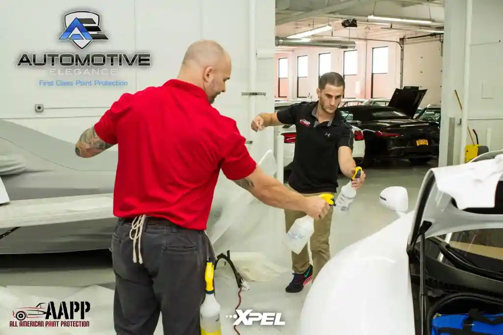 Technicians preparing paint protection film installation on a Bugatti Veyron body panel
