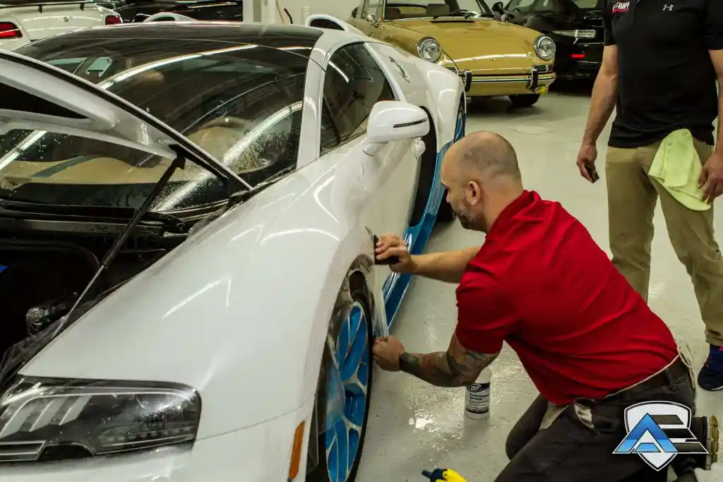 Technician installing paint protection film around the front wheel arch of a Bugatti Veyron