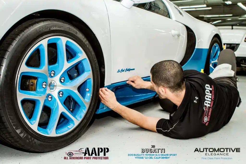 Technician applying paint protection film to the side skirt of a Bugatti Veyron