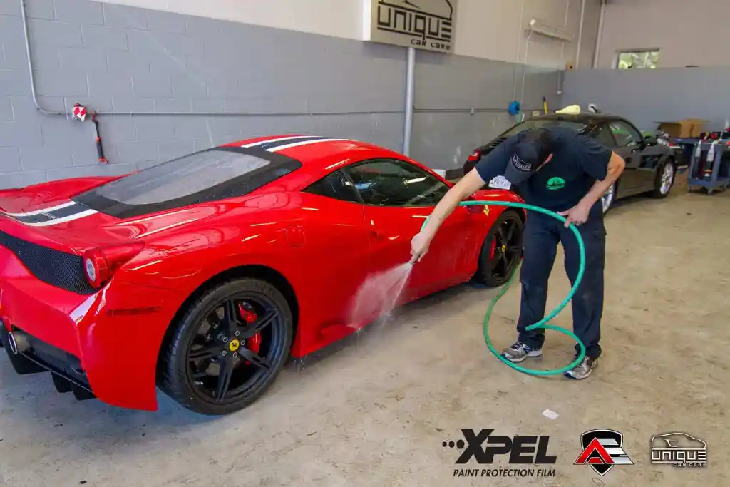 Ferrari 458 Speciale being rinsed during paint protection film preparation
