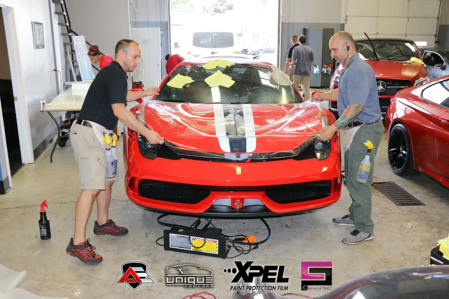 Technicians positioning paint protection film on the hood of a Ferrari 458 Speciale
