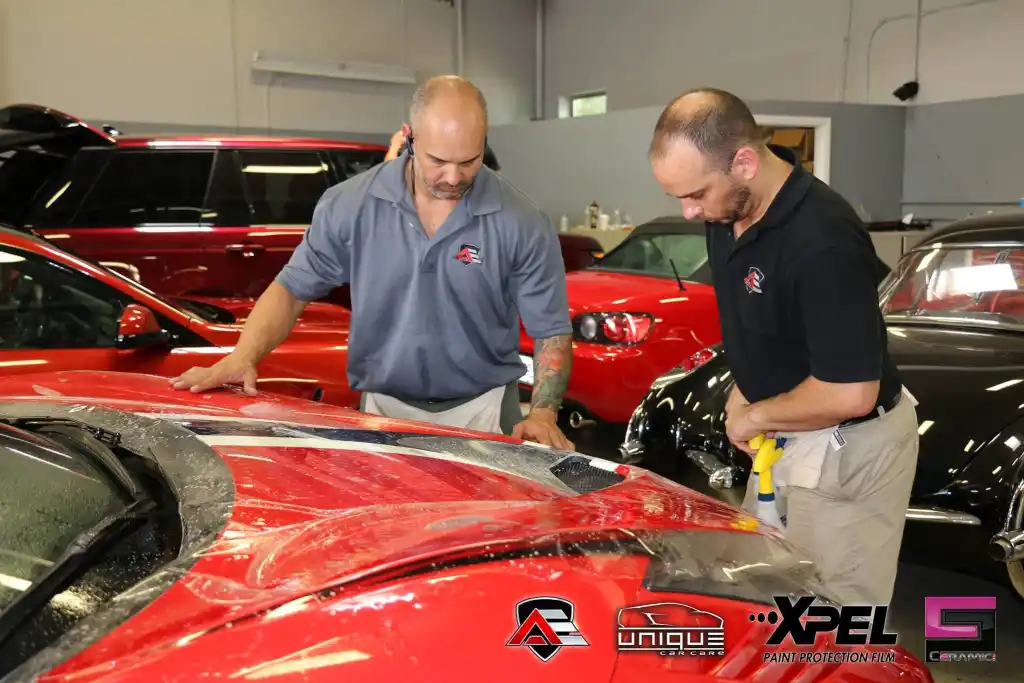 Technicians aligning paint protection film on the hood of a Ferrari 458 Speciale