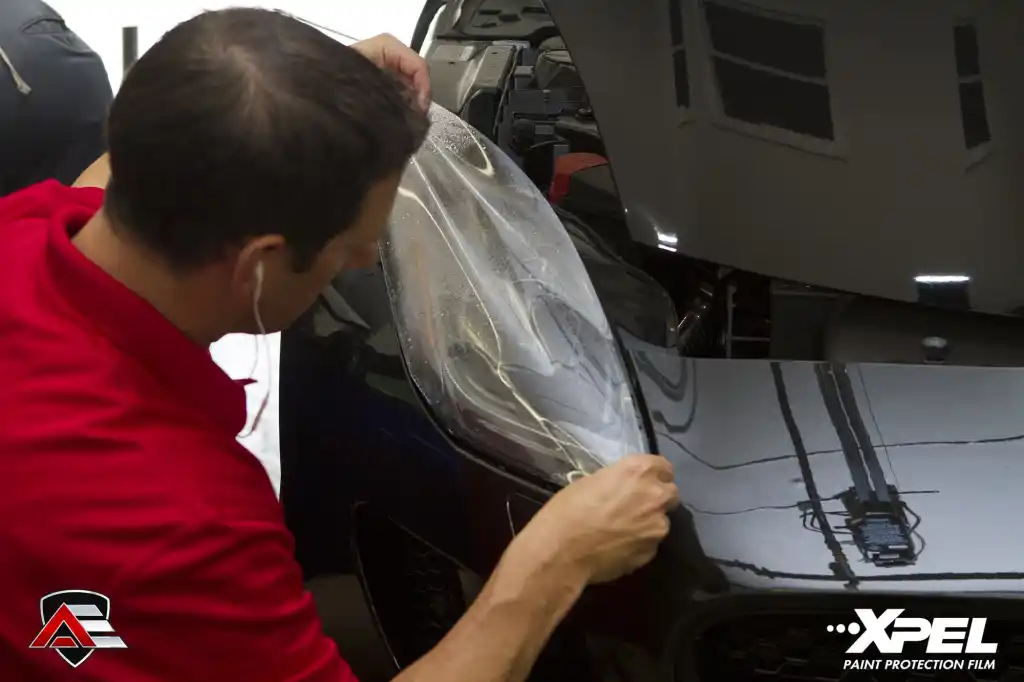 Technician installing XPEL paint protection film on a Jaguar F-TYPE R headlight