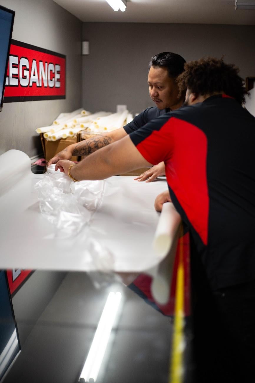 Sammy and Jaymin removing excess film from pre-cut panels in the Design Center