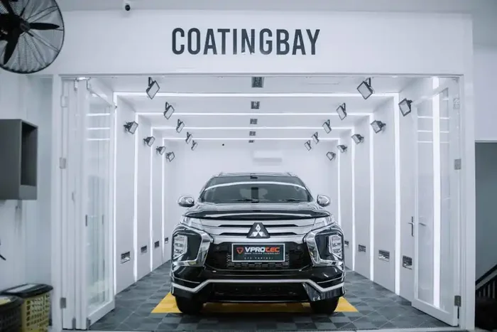 A black SUV in a brightly lit ceramic coating bay