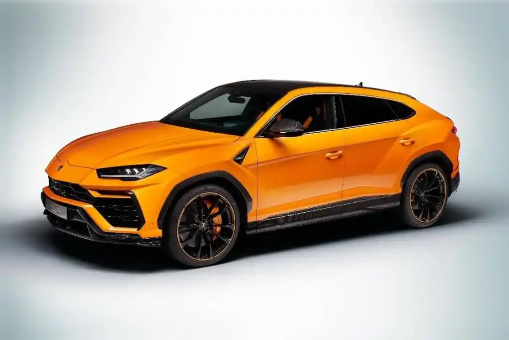 Bright orange Lamborghini Urus SUV with black roof and wheels, parked on a light gray surface.