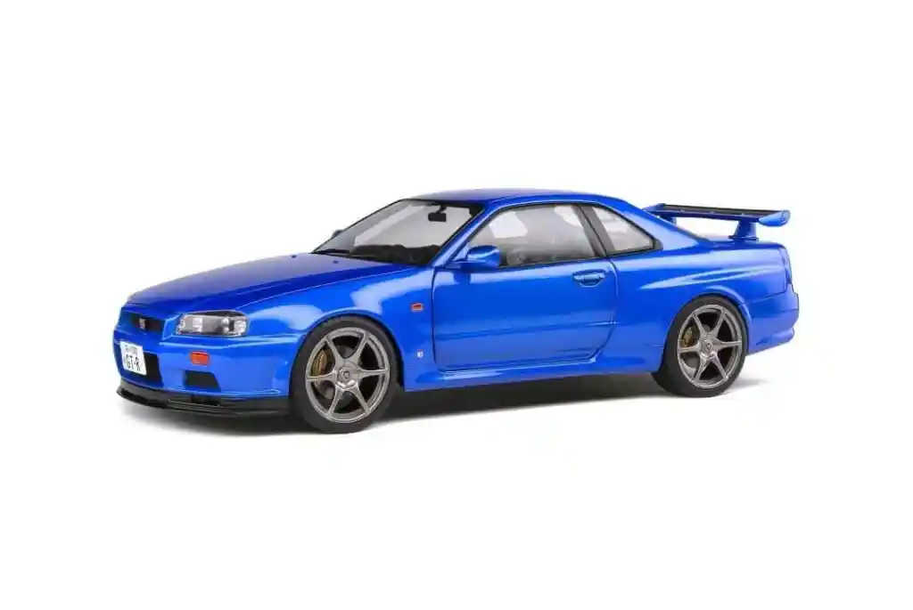 A bright blue, two-door Nissan Skyline GT-R sports car with a rear spoiler, viewed from a slightly elevated side angle.