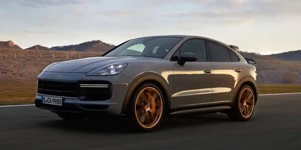 A gray Porsche Cayenne Coupé on a road with a mountainous landscape in the background.