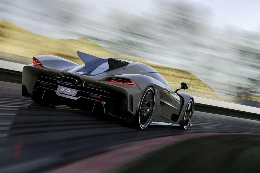 Dark grey Koenigsegg Jesko Absolut supercar speeding around a track, with blurred desert hills in the background.